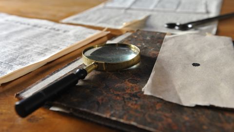 Newspaper, book and magnifying glass on the table